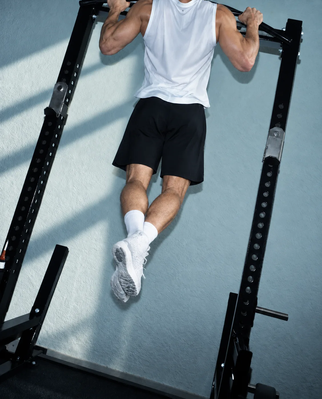 A man doing a pull-up on a squat rack